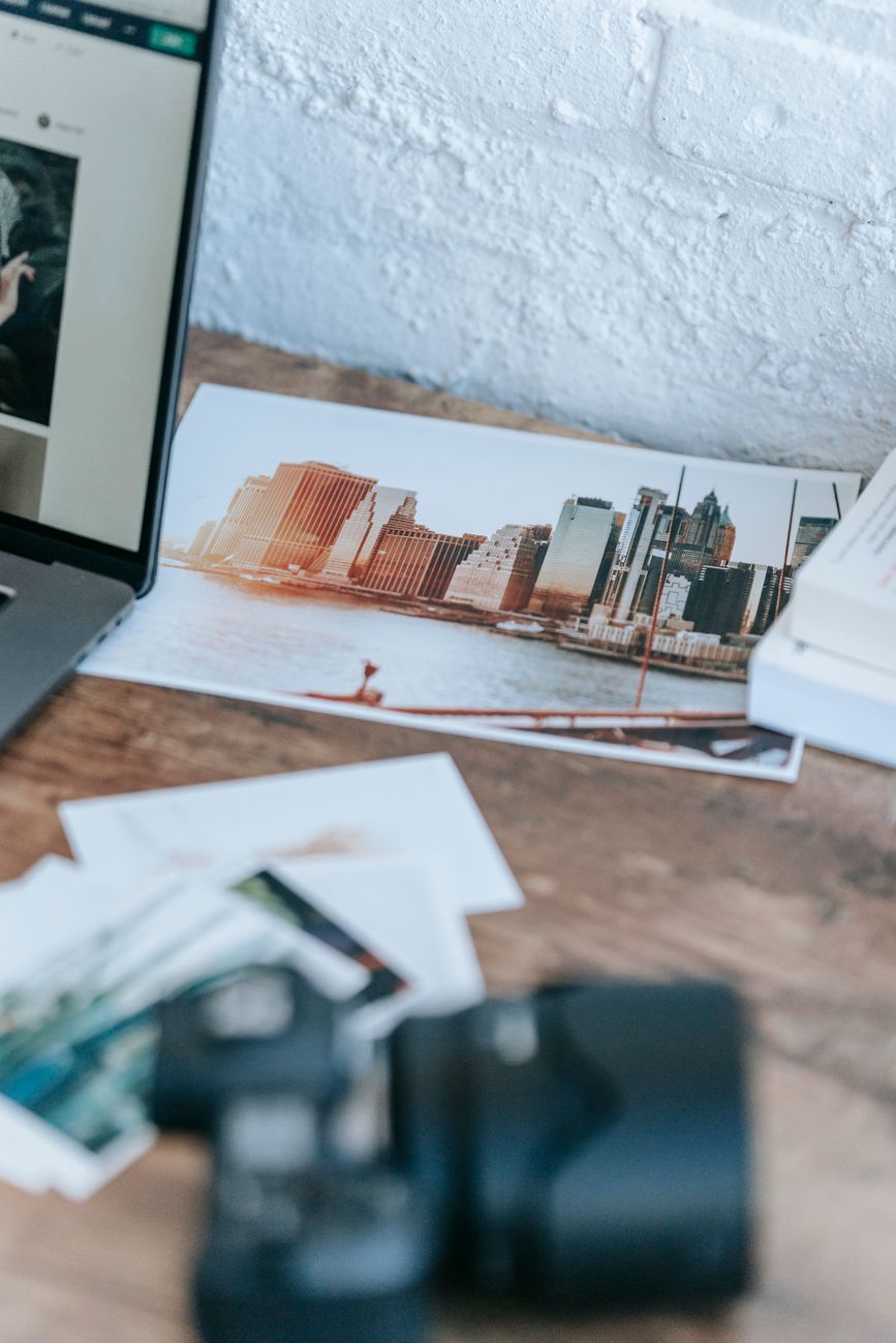 Images scattered on a desk near a laptop
